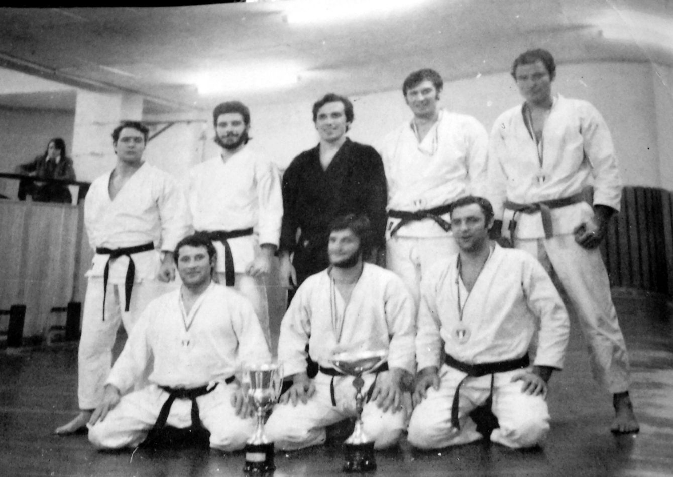 Gruppo di karateka in kimono in posa, in bianco e nero.