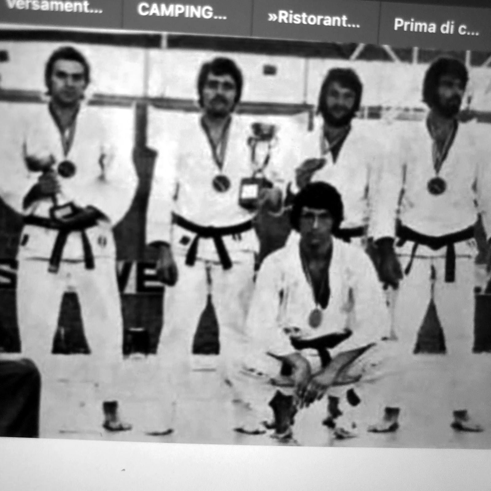 Karateka in kimono con coppa e medaglie.